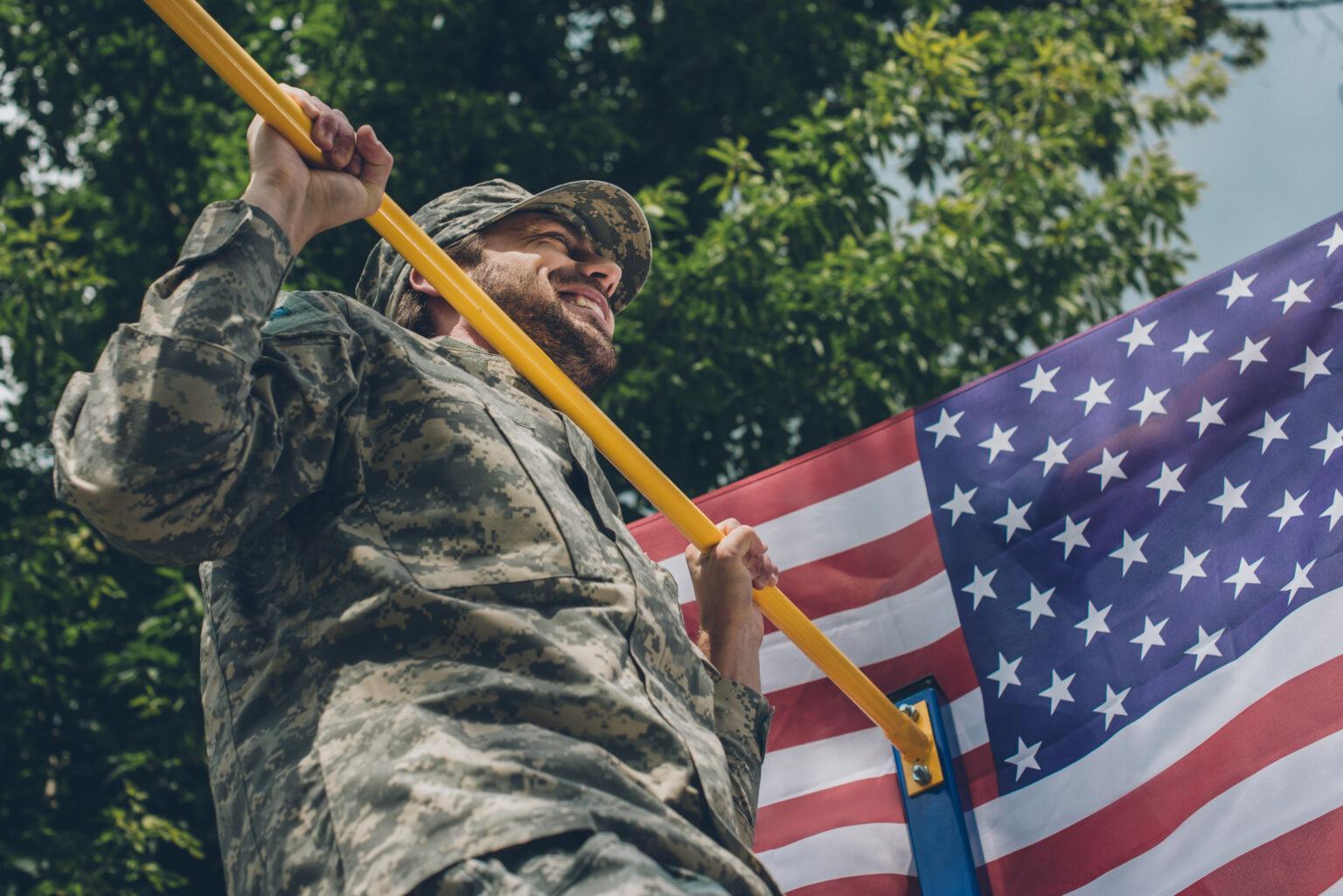 View of soldier pulling himself up on crossbar with American flag on backdrop