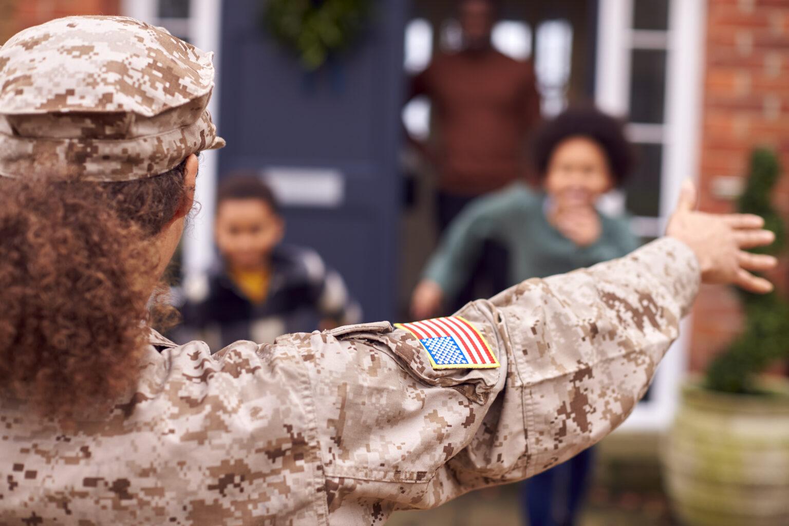 American Female Soldier In Uniform Returning Home To Family On Hugging Children Outside House